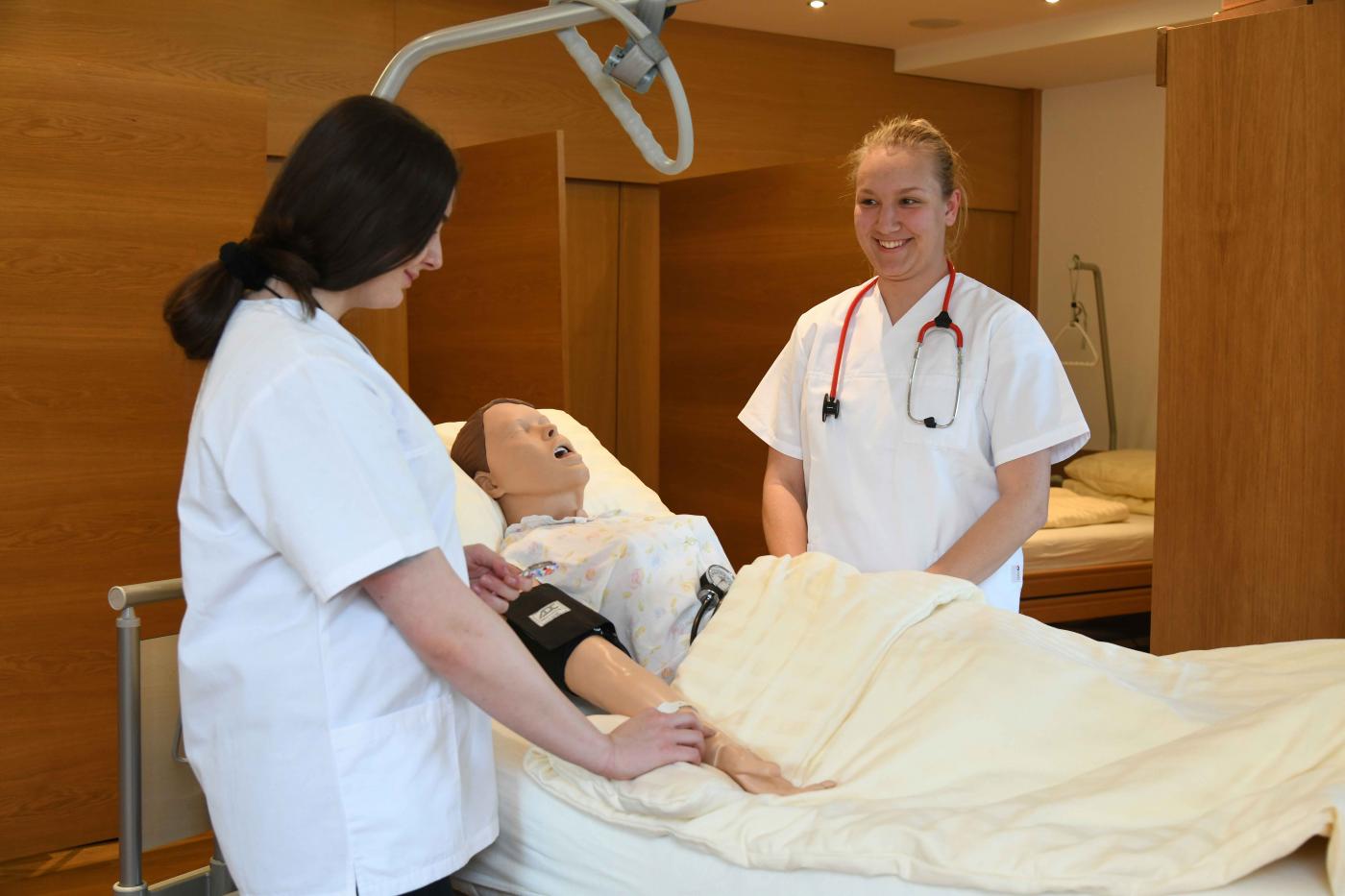 Pflegeausbildung Schülerinnen Schülerinnen bei der Pflegeausbildung - Patientenpuppe liegt im Bett